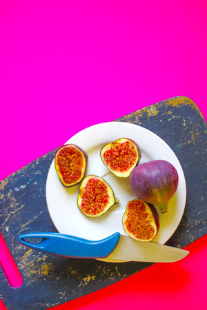 Fresh sweet ripe figs and knife on dark wooden board in a white plate.の写真素材