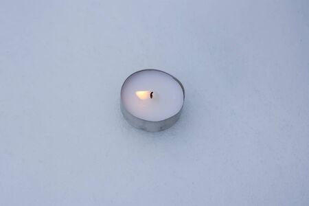 Burning tea light candle on the snow.の写真素材
