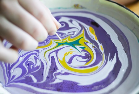 Process of creating ebru painting by colorful paints, paper and wooden stick. Bright abstract pattern in water.の写真素材