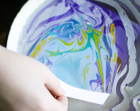 Process of creating ebru painting by colorful paints, paper and wooden stick. Bright abstract pattern in water.の写真素材