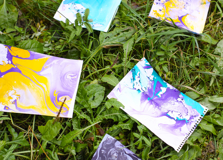 Ebru painting. Bright abstract patterns on paper sheets on green grass.の写真素材