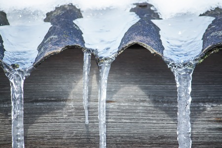 Shiny transparent icicles hanging on a roof close up.の写真素材