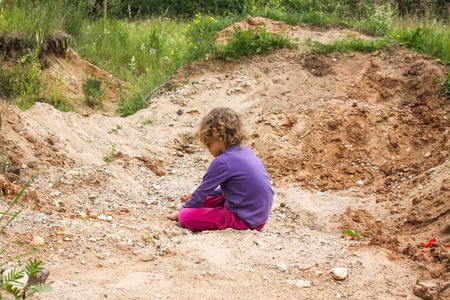 Adorable little girl playing with sand outdoors at summer in the countryside.の写真素材