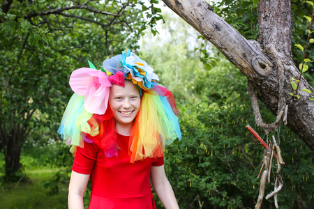 Adorable girl in colorful rainbow dress on her head playing outdoorsの写真素材