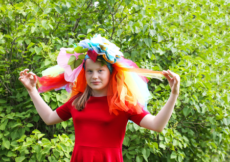 Adorable girl in colorful rainbow dress on her head playing outdoorsの写真素材