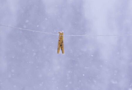 Detail of winter nature in countryside. Clothespin on a rope outdoors on snowfall background.の写真素材