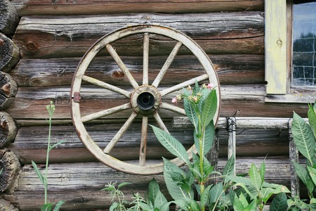 Weathered wall of old barn with wood coach wheel.