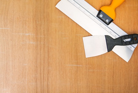 Two spatulas for home repair. Wide and narrow tools on wooden background.