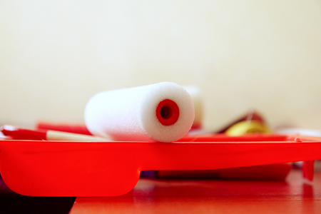 Home repair tools. Foam rollers for wall coloring in plastic container close up.の写真素材