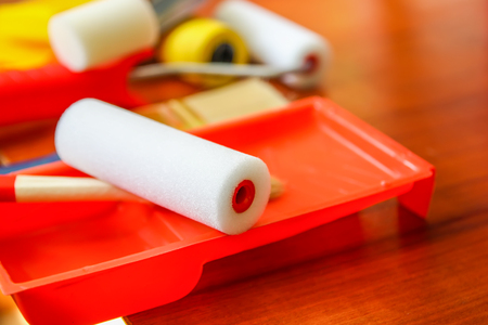 Home repair tools. Foam rollers for wall coloring in plastic container close up.の写真素材