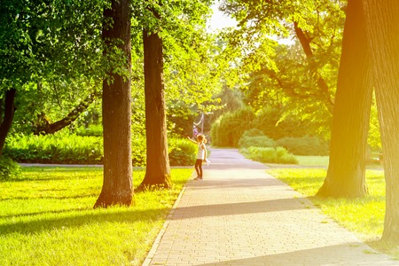 Little girl walking in beautiful city park in sunset soft light.の写真素材