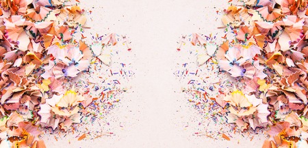 Wooden pencil shavings and colorful crumbs of graphite from sharpener on soft pink paper background. Top view. Design elements for poster, banner, cards.の写真素材