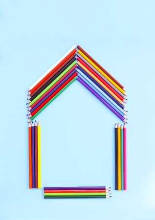 Color pencils in a shape of house on light blue background. Back to school design elements.の写真素材