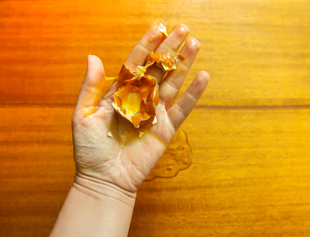 Raw smashed egg in a hand.の写真素材