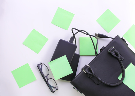 Composition with black bag, external hard disks, colorful paper empty stickers and glasses. Business...