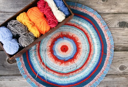 Knitted striped mat and colorful skeins of wollen yarn on wooden background.の写真素材