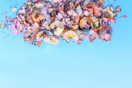Wooden pencil shavings and colorful crumbs of graphite from sharpener on soft blue pastel paper background. Top view. Design elements for poster, banner, cardsの写真素材