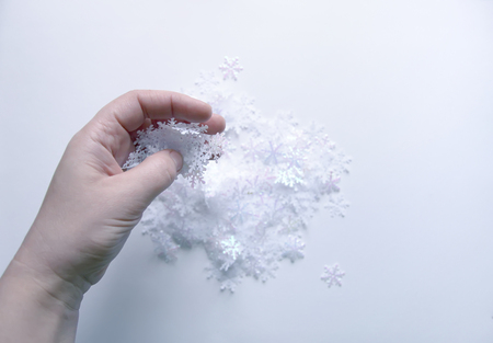 White artificial snowflakes in a woman's hand on soft lightの写真素材