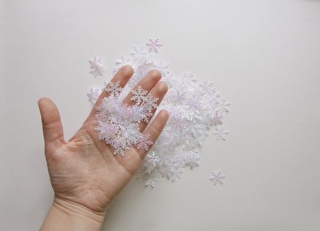 White artificial snowflakes in a woman's hand on soft lightの写真素材