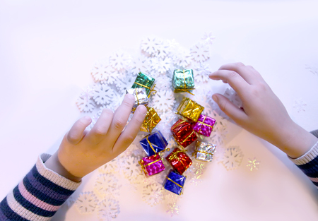 Small colorful gift boxes in child's hands. Christmas and New Year decorations process.の写真素材