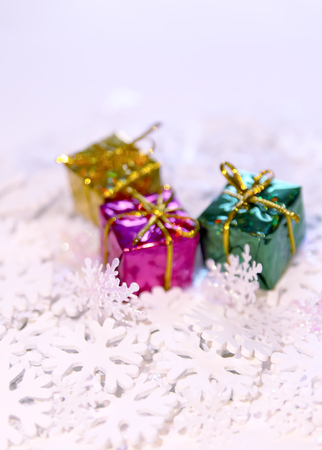 Group of small bright colorful gift boxes on white artificial snowflakesの写真素材