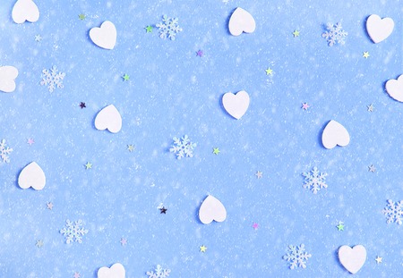 Decorative Christmas and New Year soft blue background with white wooden hearts and snowflakes. Festive template. Greeting card with copy space. Snowfall effect.の写真素材