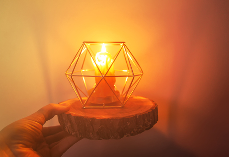 Warm light of hand made natural bee wax dying candle in a candleholder on wooden slice.の写真素材