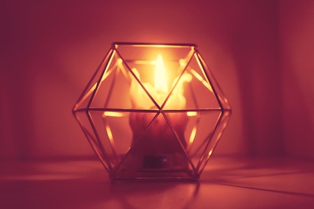 Warm light of hand made natural bee wax dying candle in a candleholder on wooden slice.の写真素材
