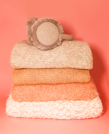 Pile of warm autumn and winter knitted sweaters on a home wardrobe shelf. Modern fashion clothes in...