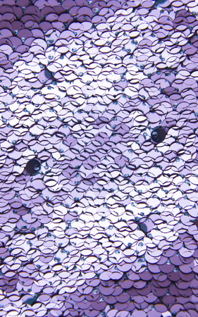 Bright shiny rugged texture of colorful sequins in purple colors. Fashion fabric background.