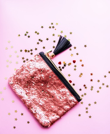 Bright composition of fashion accessories. Glitter sequins purse and decorative tinsel. Different objects on soft pastel background. Flat lay, top view.の写真素材