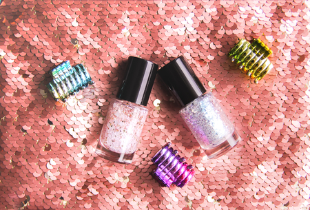 Bright composition of fashion accessories. Nail polishes and hair clips on sequins texture background. Objects on soft pastel background. Flat lay, top viewの写真素材
