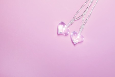 Two small glass transparent hearts on soft pink background. Valentine's day symbol. Decorative element. Festive Valentine card.の写真素材