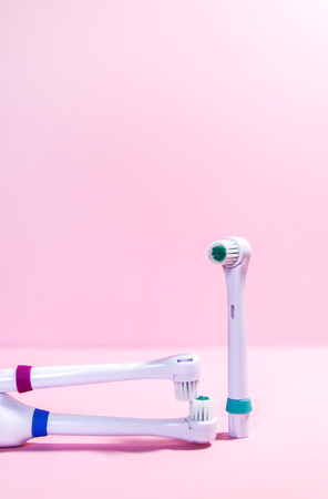 Two electrical toothbrushes on a soft light pink background.の写真素材