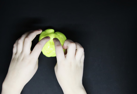 Girl playing with yellow slime in her hands.の写真素材