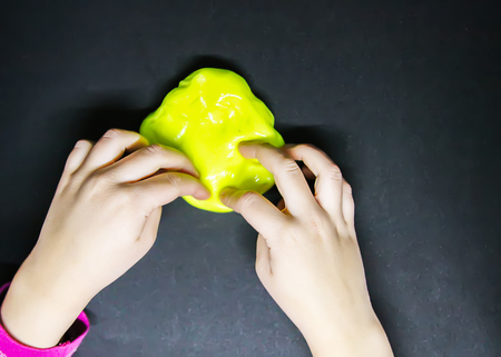 Girl playing with yellow slime in her hands.の写真素材