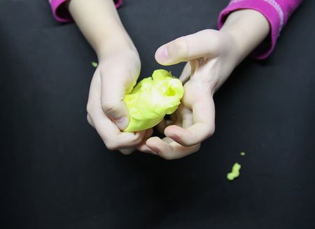 Girl playing with yellow slime in her hands.の写真素材
