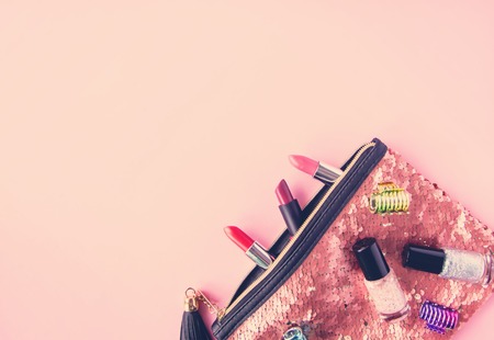 Bright composition of fashion accessories. Glitter sequins cosmetic bag with lipsticks and nail polishes. Object on soft pastel background. Flat lay, top view.の写真素材