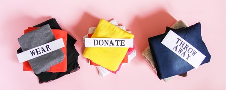 Clothes sorting in home wardrobe for donation, wearing and discard with paper notes on soft pink background.の写真素材