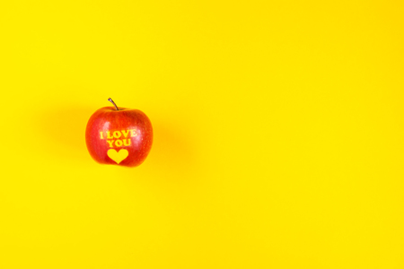 Ripe apple with words I LOVE YOU on bright yellow background.の写真素材
