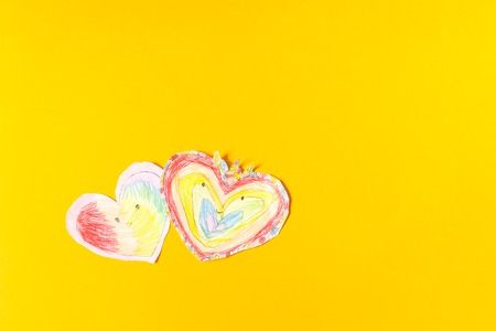 Paper hearts on bright yellow paper background. Child's creation for Valentine's day.の写真素材