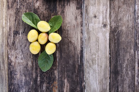 Yellow plums. Fresh ripe sweet fruits on old wooden boards rough background.の写真素材