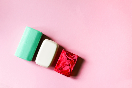 Different homemade coloful soap on soft pink background.