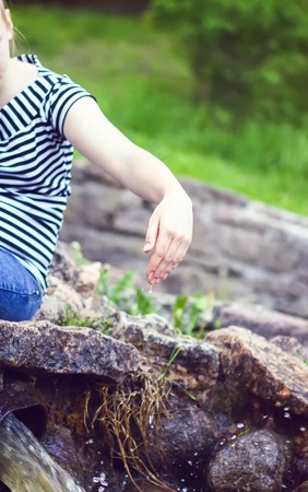 Woman hands in cold transparent water stream in supring park