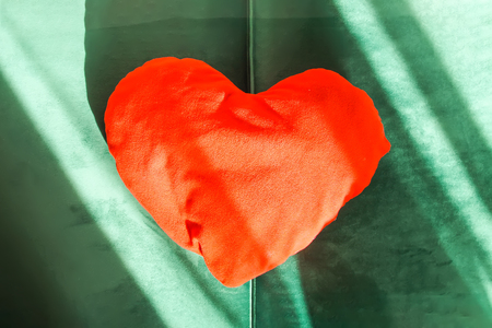 Heart shaped small decorative pillow on soft green pouffe. Modern interior cozy design elementの写真素材