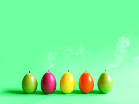 Traditional Easter decor. Group of bright burning paraffin candles in the shape of colorful eggs on...