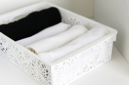 Home wardrobe with different clothes. Small space organization. Vertical storage in a plastic box.