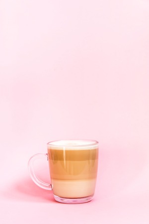 Hot coffee latte transparent glass cup on a soft pink background.の写真素材