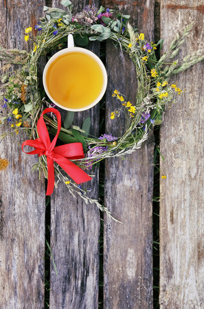Herbal tea of medical plants in a cup on weathered wooden boards outdoors.の写真素材