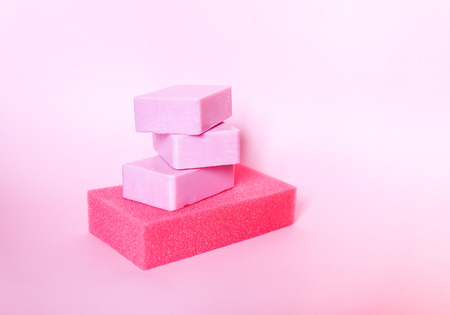 Colorful washcloths and bars of soap on a soft pink background. Accessories for body care and hygiene.の写真素材